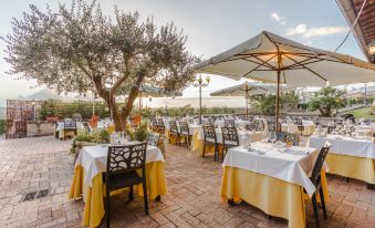 an outdoor dining area with several tables and chairs set up for guests to enjoy a meal at Hotel Ristorante la Pergola