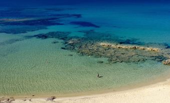 a beautiful beach with clear blue water , umbrellas , and sun loungers , as well as people enjoying the scenery at Hotel la Playa