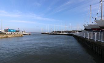 a dock on the water with a sailboat in the distance and a clear blue sky above at Levante