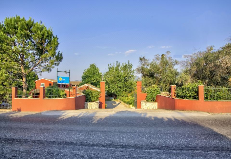 a brick driveway leading up to a house with a gate , surrounded by trees and bushes at Blue Dream Apartments