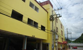 a city street with a yellow building on the corner , surrounded by power lines and parked cars at Sirasit 999 Mansion