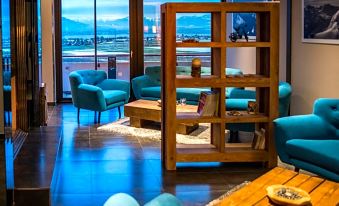 a modern living room with blue chairs , wooden tables , and large windows offering views of the ocean at Everness Hotel & Resort