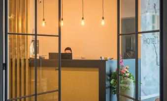 a modern office reception area with a desk , two people behind it , and hanging lights at Hotel Huron