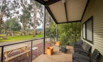 a wooden deck with a view of trees and a picnic table , surrounded by lounge chairs at Big4 Breeze Holiday Parks - Eildon