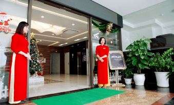 "a woman in a red dress standing outside a hotel , holding a green sign that reads "" welcome .""." at Binh Minh Hotel