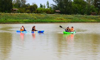 three people are kayaking on a river , one in a blue kayak and two in green kayaks at Lalanasi Lodge