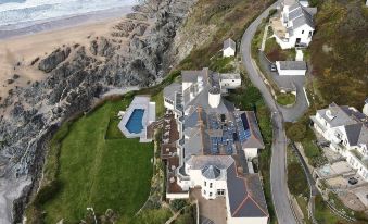 aerial view of a beach town with houses , a pool , and a grassy area near the ocean at Watersmeet Hotel
