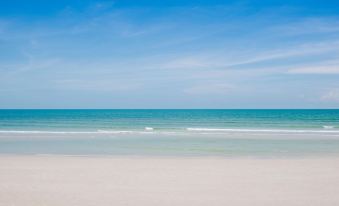 a serene beach scene with a clear blue sky and ocean , captured from a low angle at The Yana Villas Hua Hin