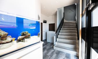 a modern living room with a large fish tank in the corner , surrounded by stairs and hardwood floors at Volcano