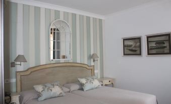 a well - decorated bedroom with a wooden bed , white and gray striped wallpaper , and a window above the bed at Hotel Villa Maria