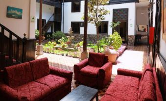 a modern , well - decorated living room with red couches and chairs , surrounded by lush greenery and a courtyard at Hotel Casablanca