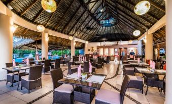 a large restaurant with wooden tables and chairs , surrounded by a bar and bar stools at Bahia del Sol Beach Front Boutique Hotel