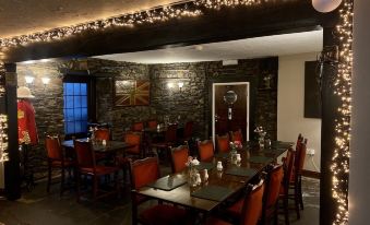 a dining room with a long wooden table surrounded by red chairs , creating a warm and inviting atmosphere at The Mary Tavy Inn