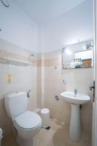 a small bathroom with a toilet , sink , and mirror , as well as some toiletries on the counter at Hotel Summery