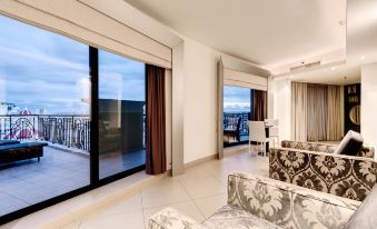 a modern living room with large windows , white walls , and beige carpet , featuring comfortable seating arrangements and a dining area at AX The Palace