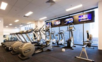 a well - equipped gym with various exercise equipment , including treadmills , elliptical machines , and stationary bikes , arranged in rows at The Larwill Studio Melbourne - Art Series