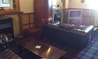 a cozy living room with leather couches , a fireplace , and a clock on the wall at Polochar Inn