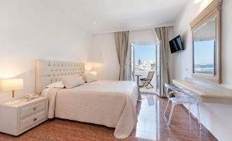 a modern bedroom with a large bed , white furniture , and a sliding glass door leading to a balcony at Paliomylos Spa Hotel