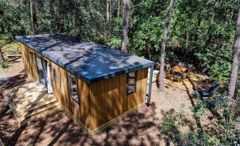 a small wooden house nestled in a forest , surrounded by trees and a dirt road at Green Resort