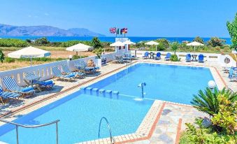 a large swimming pool with a flag and chairs is surrounded by mountains and the ocean at Palladion