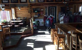 a wooden bar with stools and tables , as well as a dining area with tables and chairs at Kohl's Resort