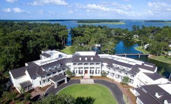aerial view of a large white building surrounded by trees and a lake in the background at Montage Palmetto Bluff