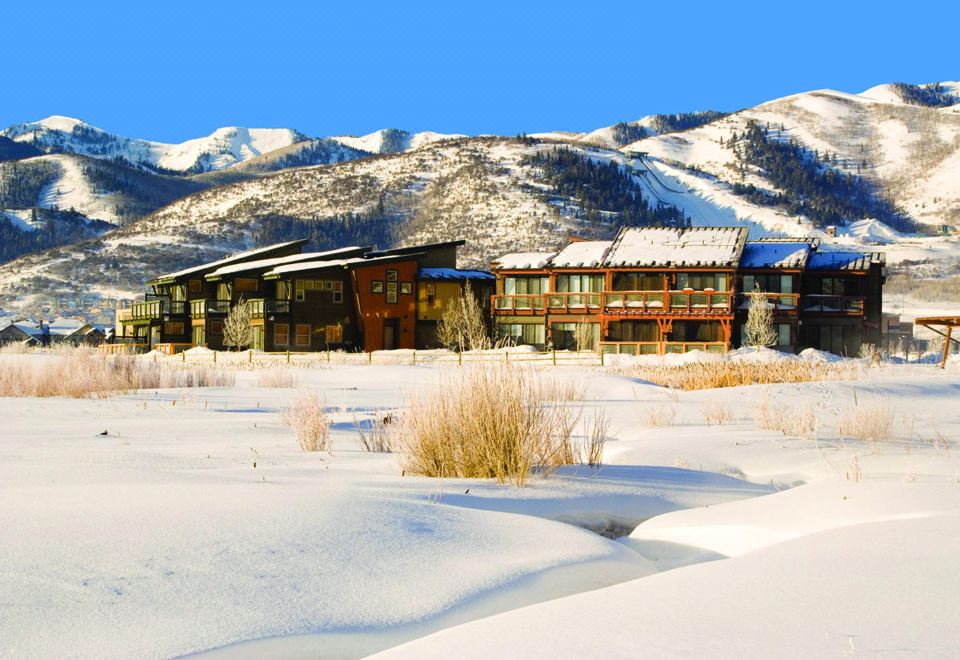 a large , modern building with a red roof is surrounded by snow - covered mountains in the background at Newpark Resort