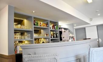 a bar area with a white counter and shelves filled with various bottles and glasses at Hob le Cheval Blanc