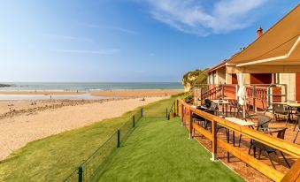 a house with a deck and patio area is overlooking a beach with chairs and tables at Hotel SanMar