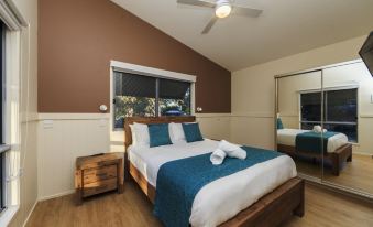 a spacious bedroom with a large bed , wooden furniture , and a ceiling fan above the bed at Reflections Scotts Head - Holiday Park