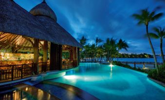 a resort with a large pool surrounded by palm trees , a gazebo , and a gazebo overlooking the ocean at Shangri-Las le Touessrok Resort and Spa