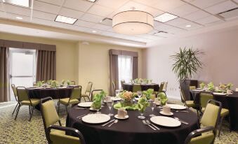 a well - decorated banquet hall with round tables covered in black tablecloths and set for a formal event , surrounded by chairs at Hilton Garden Inn Akron-Canton Airport