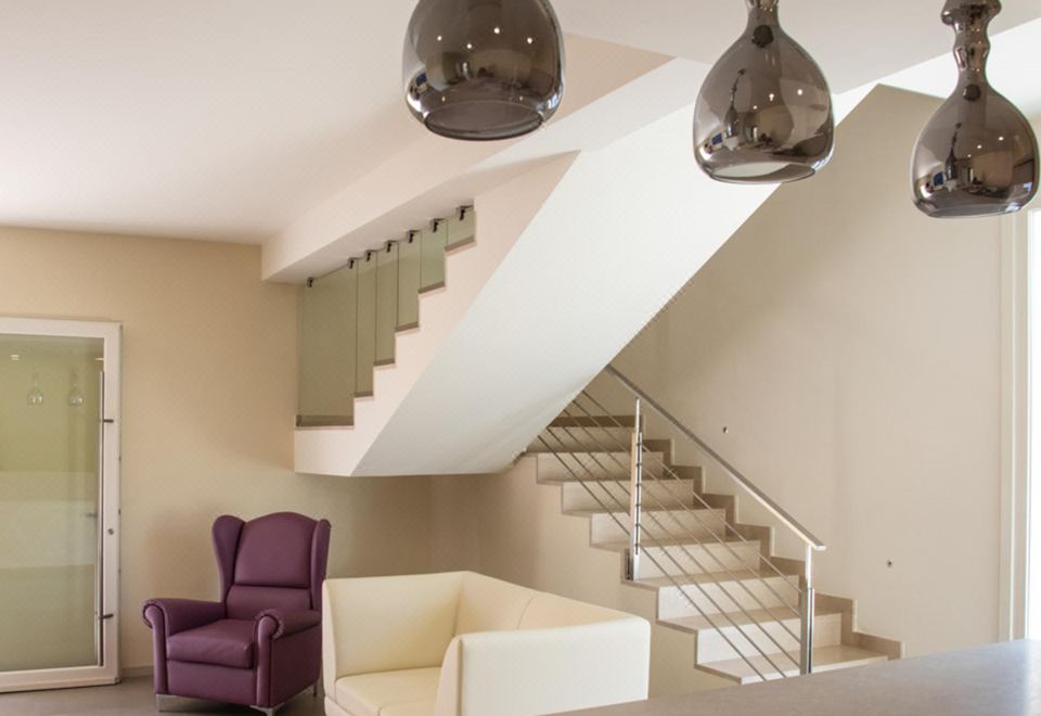 a modern living room with a purple armchair and a white staircase leading to the second floor at Hotel Royal