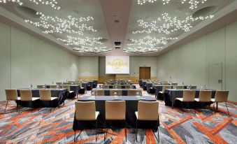 a large conference room with multiple rows of tables and chairs , a projector screen , and orange carpet at Hard Rock Hotel Tenerife