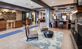 a modern hotel lobby with comfortable seating , a bar area , and a reception desk , all situated in a spacious space at Best Western Plus Williston Hotel  Suites