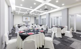 "a large conference room with multiple round tables , chairs , and a screen displaying the words "" meeting room .""." at Hotel Frontera Clásico