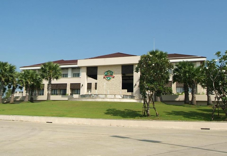 a large building with a green sign on the front , surrounded by trees and grass at Suwan Golf and Country Club