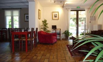 a dining room with a red couch , dining table , chairs , and a television mounted on the wall at Hotel Ermitage