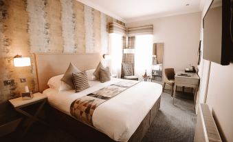 a large bed with a brown headboard and white linens is in the middle of a room at The Seafield Arms-Cullen