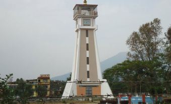 a tall , white and brown clock tower with a traditional roof , standing in front of a mountainous landscape at Suva Hotel