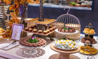A table in the center with a variety of desserts, including small cakes and cookies at Novotel Shanghai Hongqiao Gubei