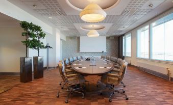 a large conference room with a long wooden table and multiple chairs arranged for a meeting at Clarion Hotel Arlanda Airport Terminal