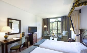 a hotel room with two beds , a desk , and a tv , all situated near a window with a view at Parador de Cangas de Onis