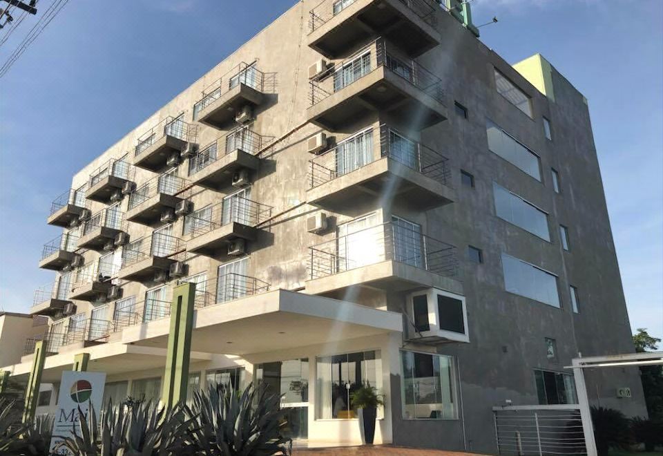 a modern building with multiple balconies , under a clear blue sky and surrounded by green plants at Maison Hotel