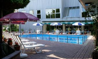 a swimming pool surrounded by chairs and umbrellas , with a building in the background at Flamengo