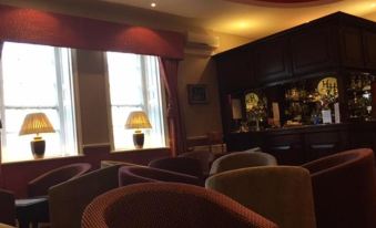 a cozy hotel room with a bar , couches , and chairs , as well as a window offering a view of the city at Hardwicke Hall Manor Hotel