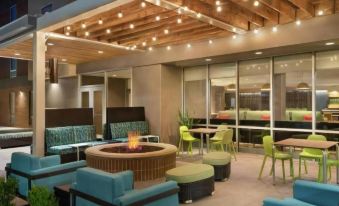 a modern outdoor space with wooden ceiling , blue and green furniture , and a fire pit at Home2 Suites by Hilton Tracy