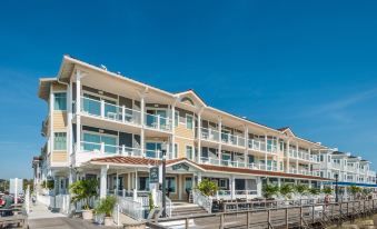 a large white building with multiple balconies and a wooden deck , situated on the beach at Bethany Beach Ocean Suites Residence Inn