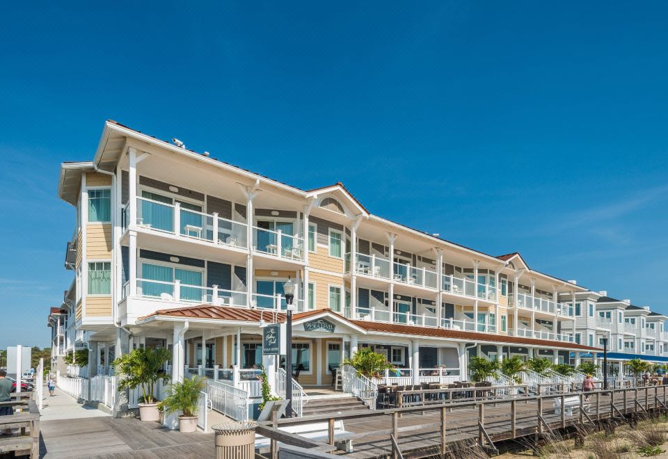 a large white building with multiple balconies and a wooden deck , situated on the beach at Bethany Beach Ocean Suites Residence Inn