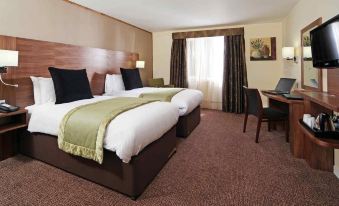 a hotel room with two beds , a desk , and a window , all set against a brown carpet at Letchworth Hall